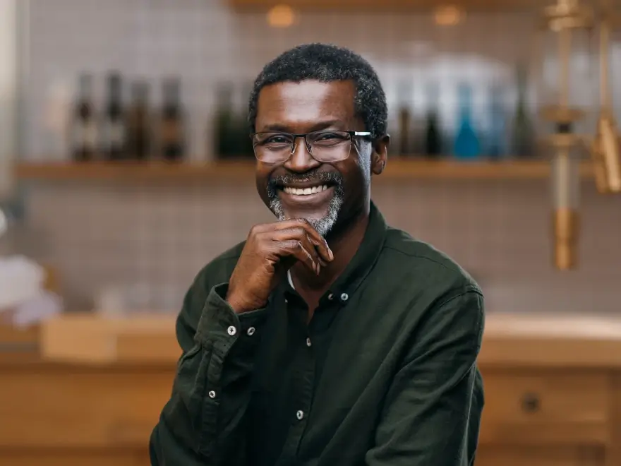 A smiling man with a beard in a dark green shirt