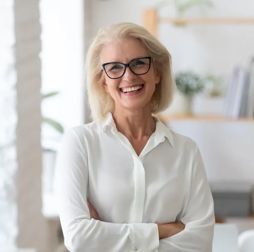 A smiling woman in a white shirt with her arms crossed