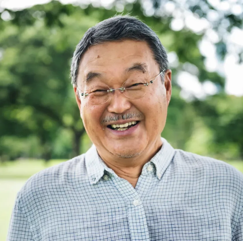 A smiling older man in a checked shirt outdoors
