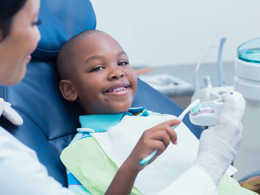A smiling boy holding a toothbrush in the dental chair