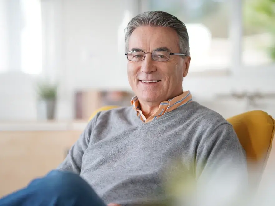 A smiling older man seated in a bright room