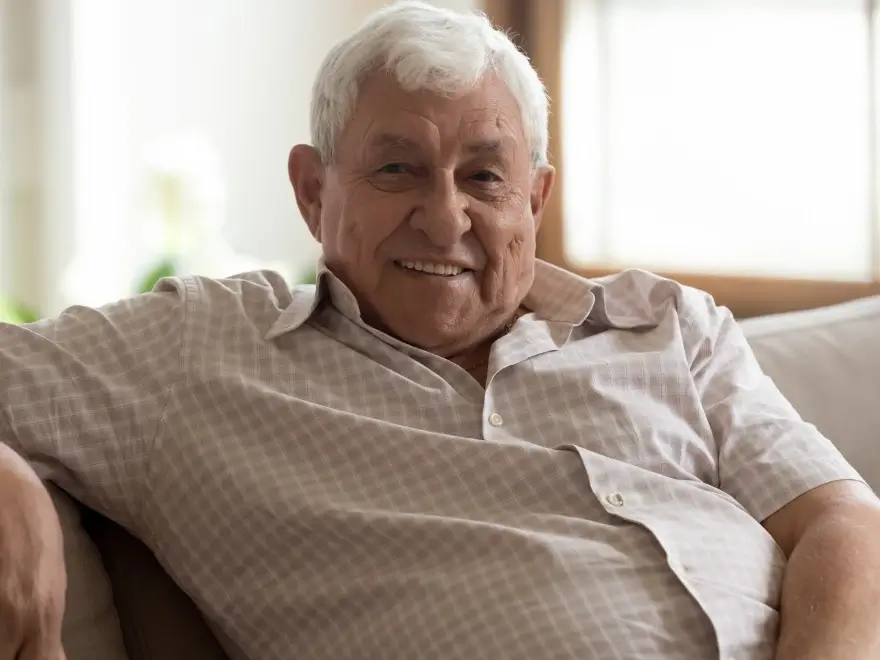 A smiling older man seated on a sofa