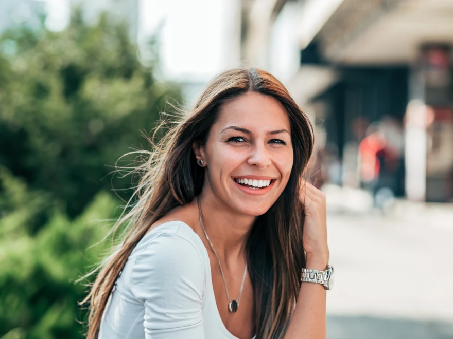 A smiling woman with long brown hair outdoors