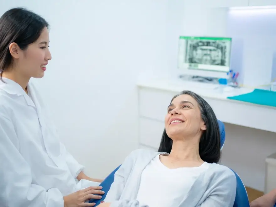 A dental team member talking with a patient reclined in the chair