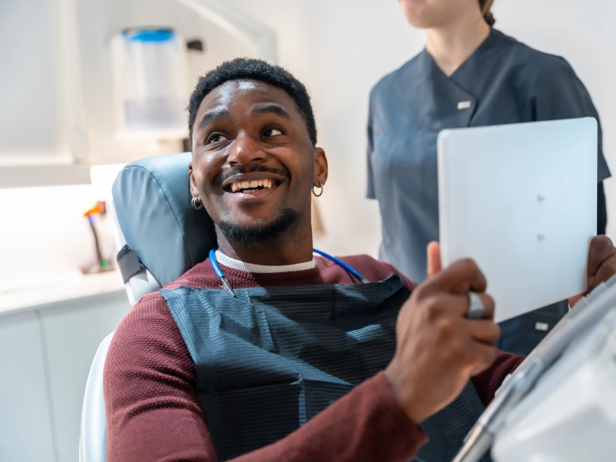 A smiling patient in the dental chair looking at a tablet
