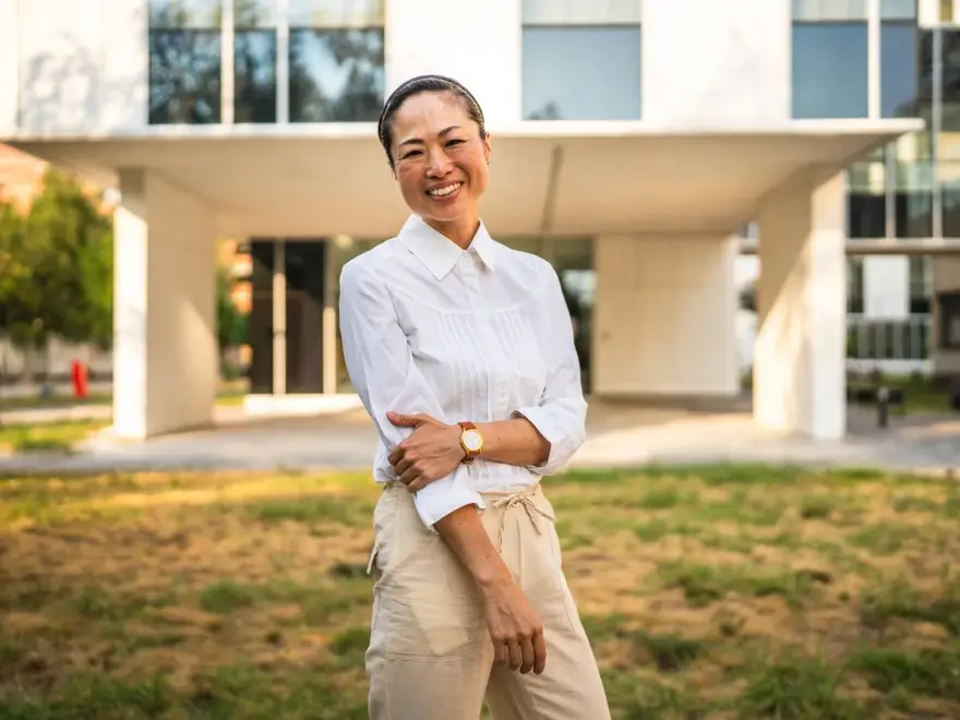 A smiling woman in a white shirt standing outside a building