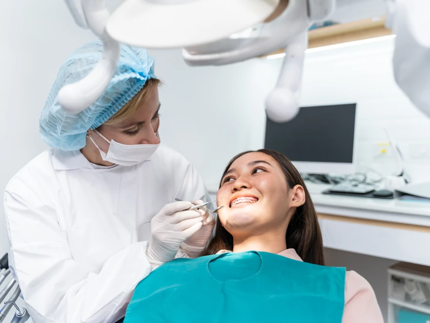 A young patient smiling while a dental team member examines her teeth