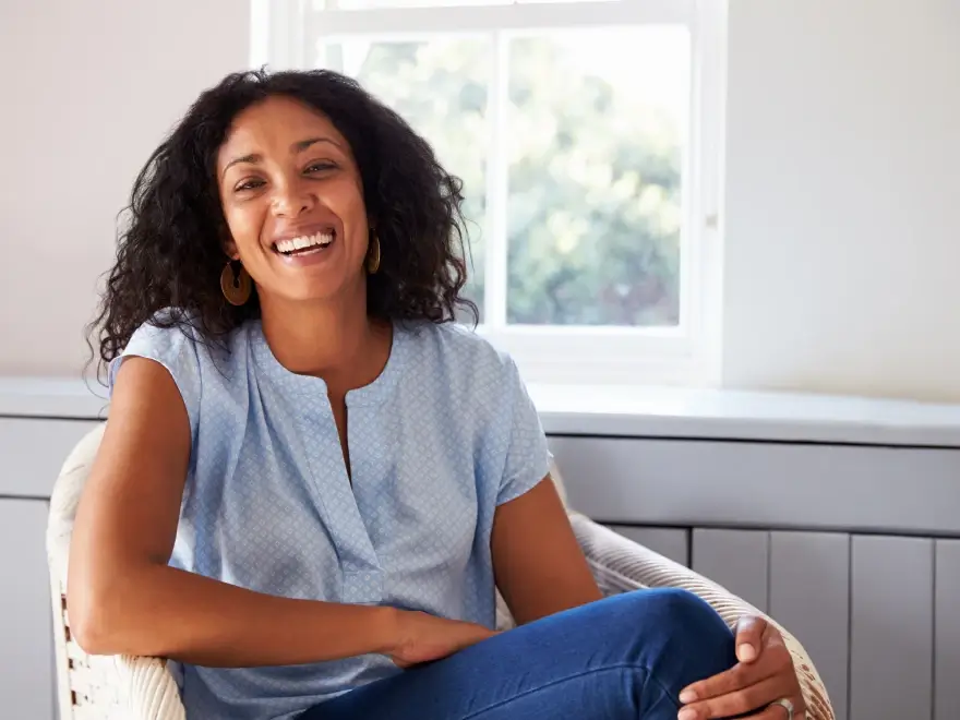 A smiling woman sitting in an armchair by a window