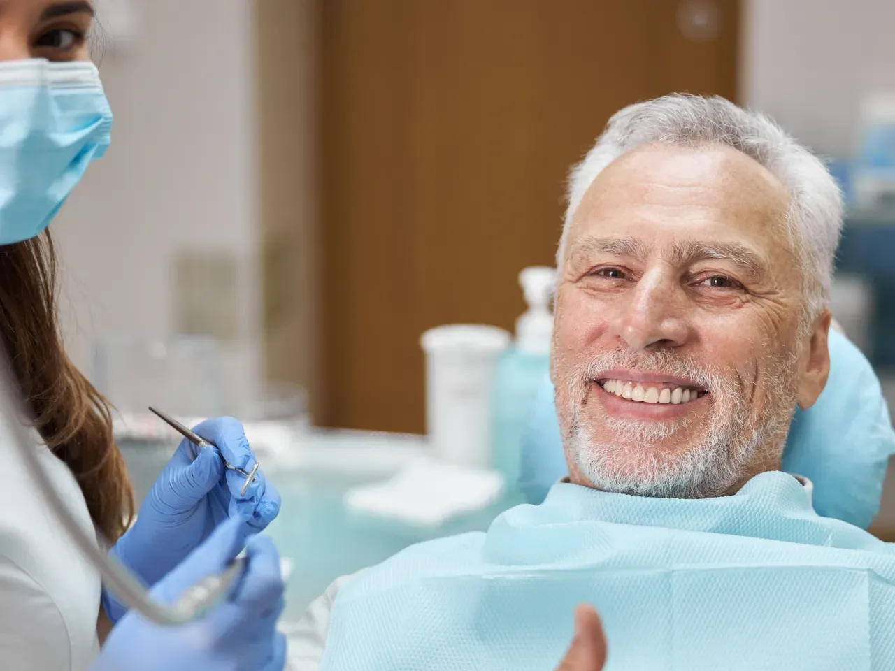 A smiling senior patient in the dental chair beside his dentist