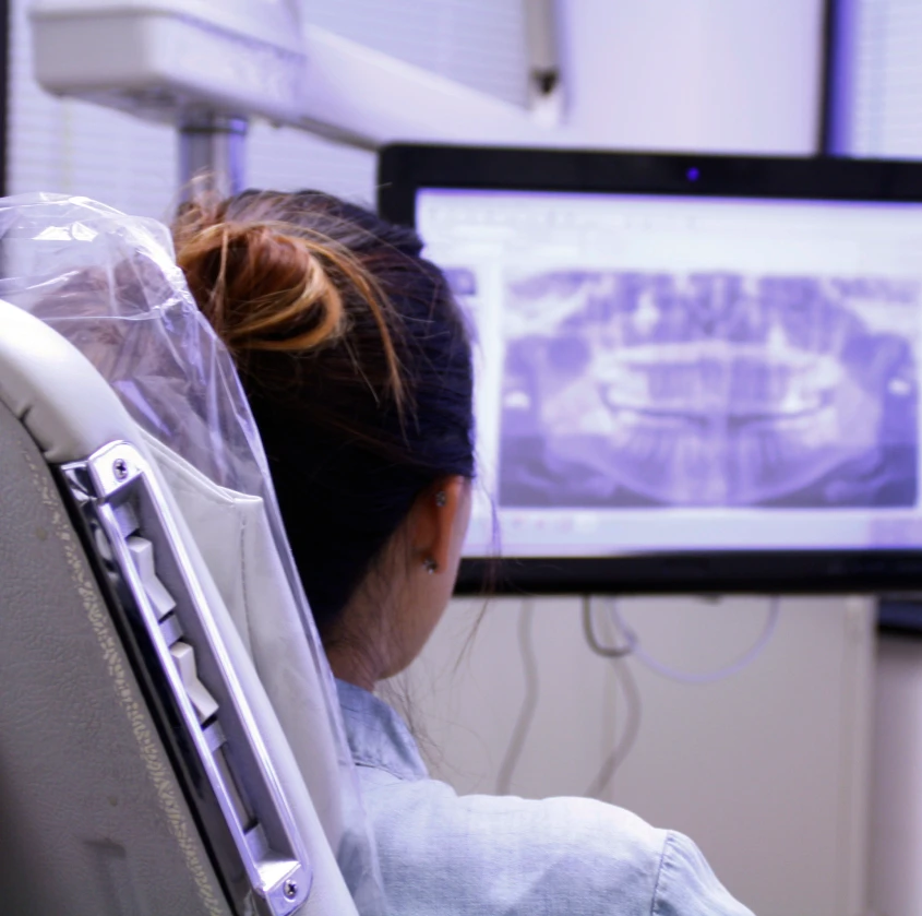 A patient looking at a panoramic dental X-ray on a monitor